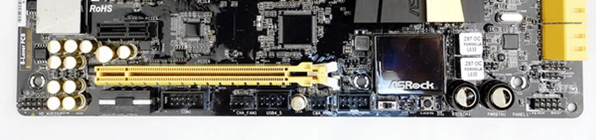 The headers of at the bottom edge consists of COM port header (to the right of the SLI/XFire power connector), two chassis fans headers, and a pair of USB 2.0 headers. At the extreme ends, we see a front panel audio header on the left; while on the right, just next to the power button, there is system panel header. The chassis speaker and power LED headers have been shifted slightly north, near to the stack of yellow SATA 6Gbps connectors.