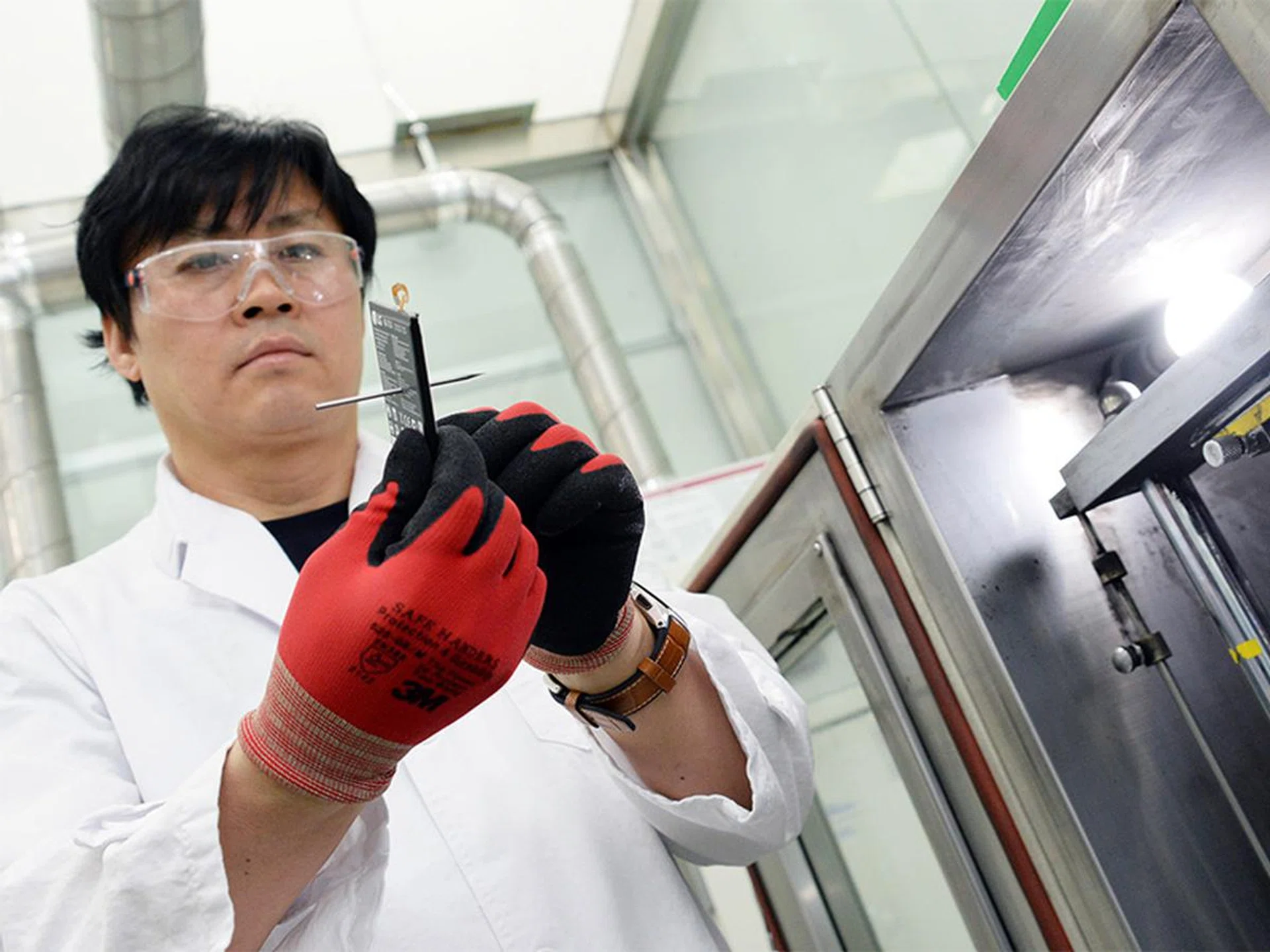 An LG technician holds up a battery that has been punctured by a nail. Image source: LG.