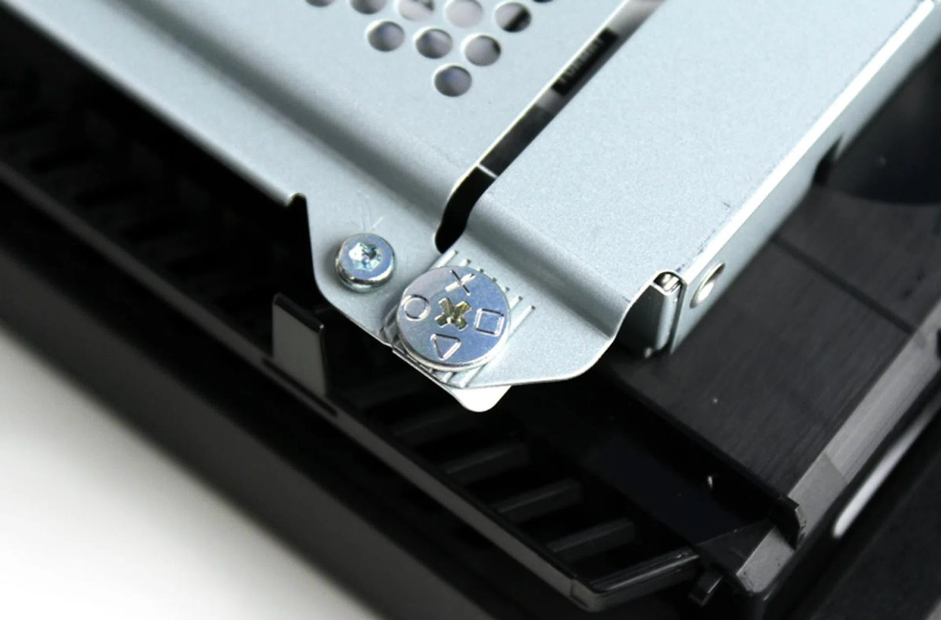 Locate the Playstation screw - it has Sony's familiar X, Triangle, Square and Circle markings on it. This screw holds the HDD chassis in place.