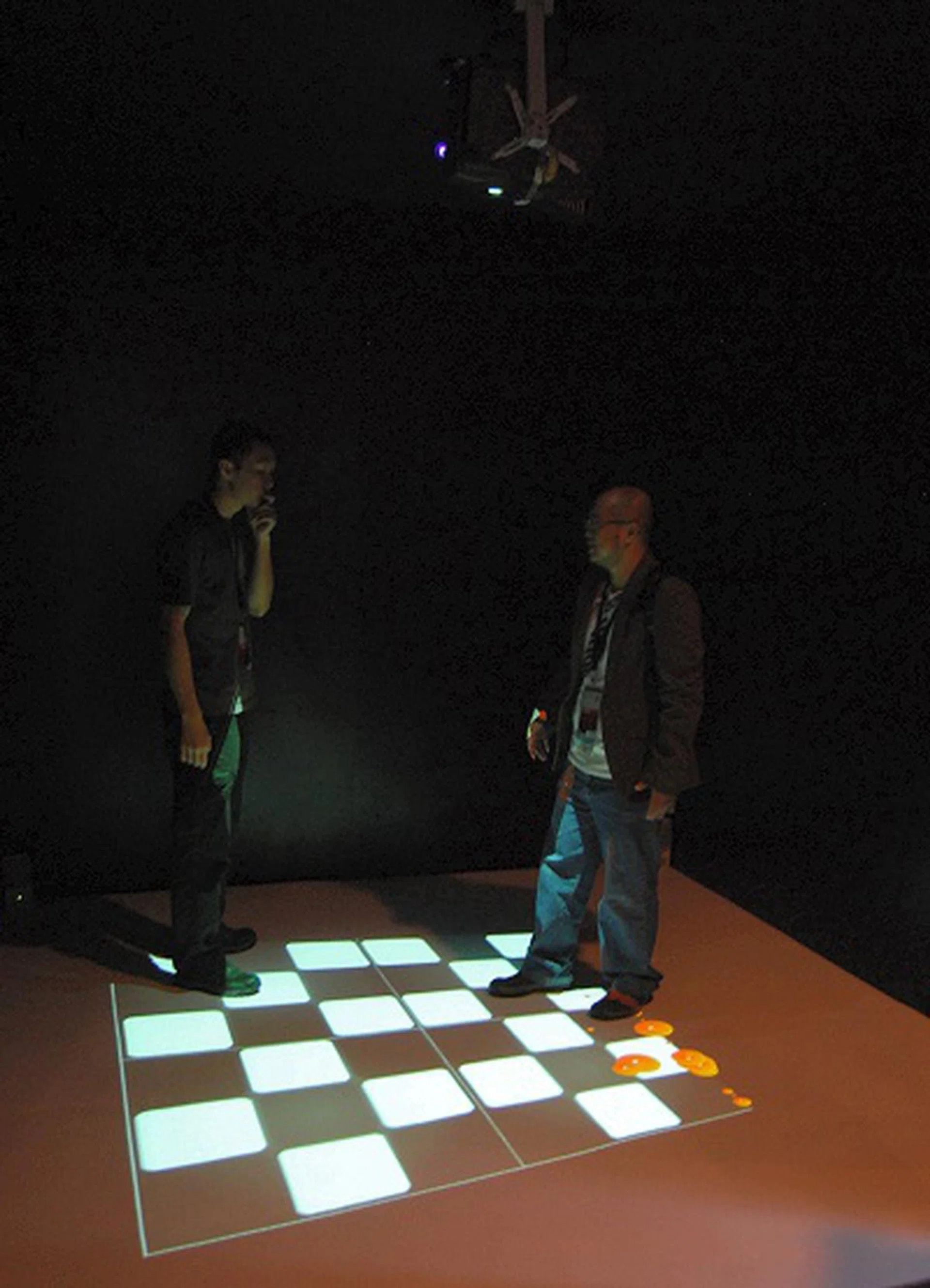 This display is of an interactive optical illusion where the board projected to the floor tilts depending where the user is and the balls on the floor follow the laws of physics as the roll around accordingly to where the board tilts. All this is facilitated by optical sensors overhead. 