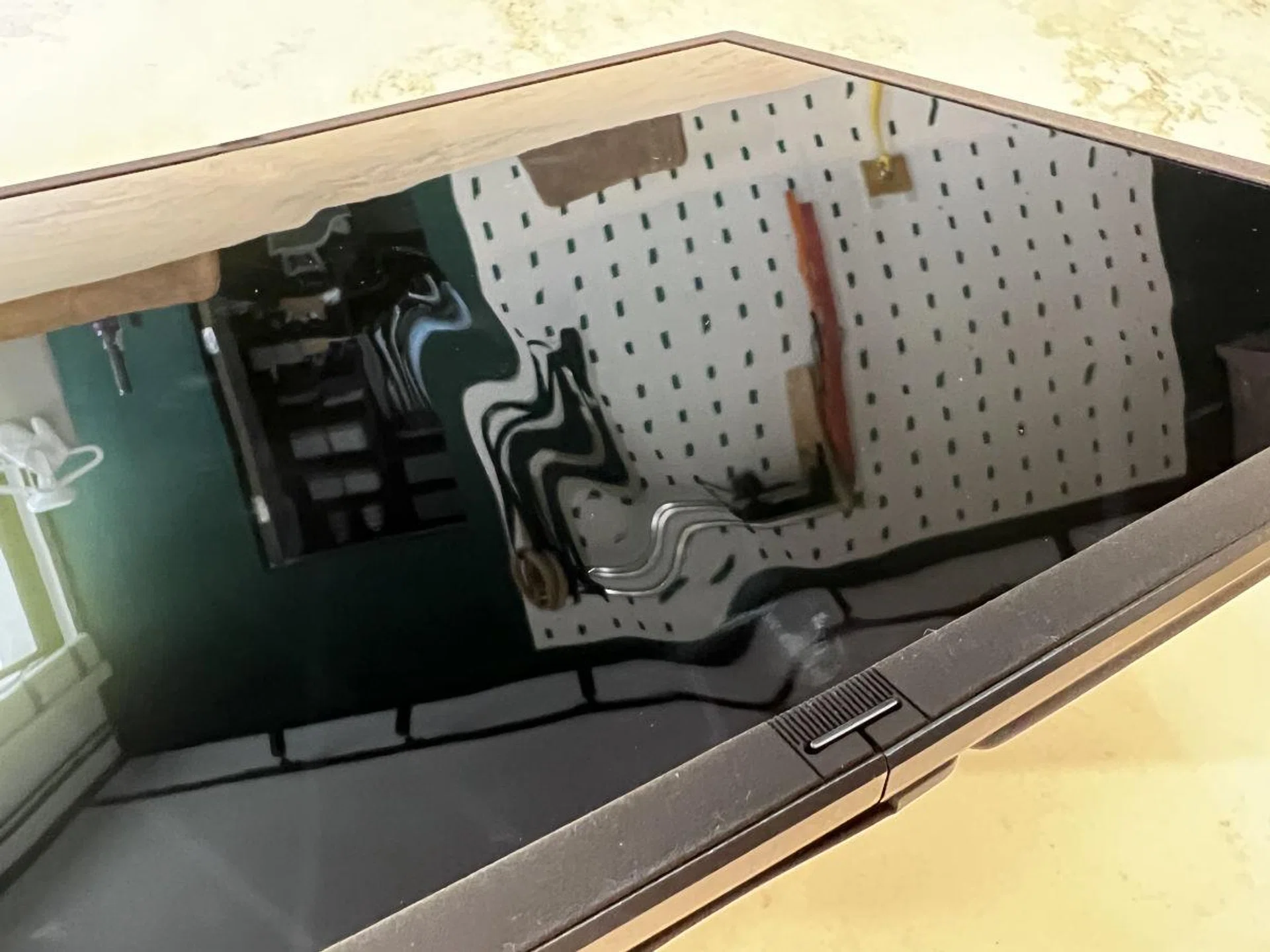 Notice the 'crease' in the middle where the reflection is distorted. This is only really visible when looking for it, but it is a soft, and wide crease, which immediately goes away when you have anything on screen at all.