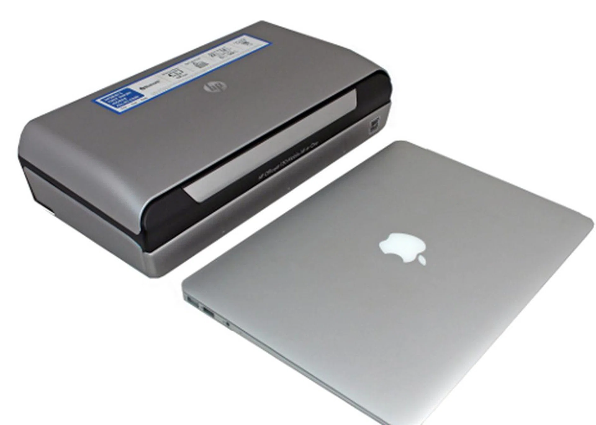 The HP Officejet 150 placed side by side with an Apple MacBook Air for relative size comparisons.