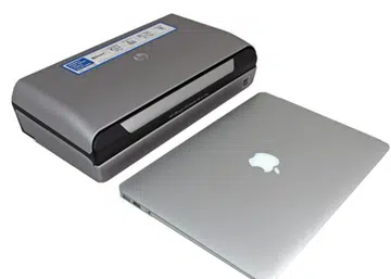 The HP Officejet 150 placed side by side with an Apple MacBook Air for relative size comparisons.