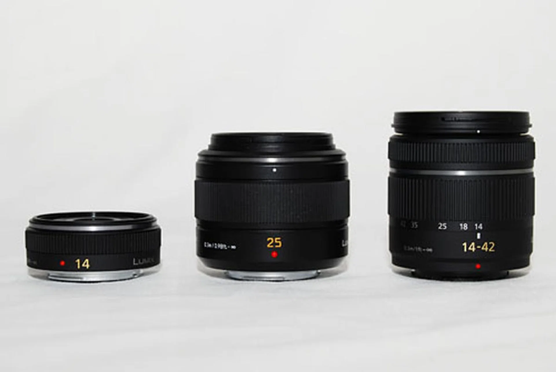 The 25mm (center) in comparison with Panasonic's 14mm (left) pancake lens and 14-42mm kit lens (right).