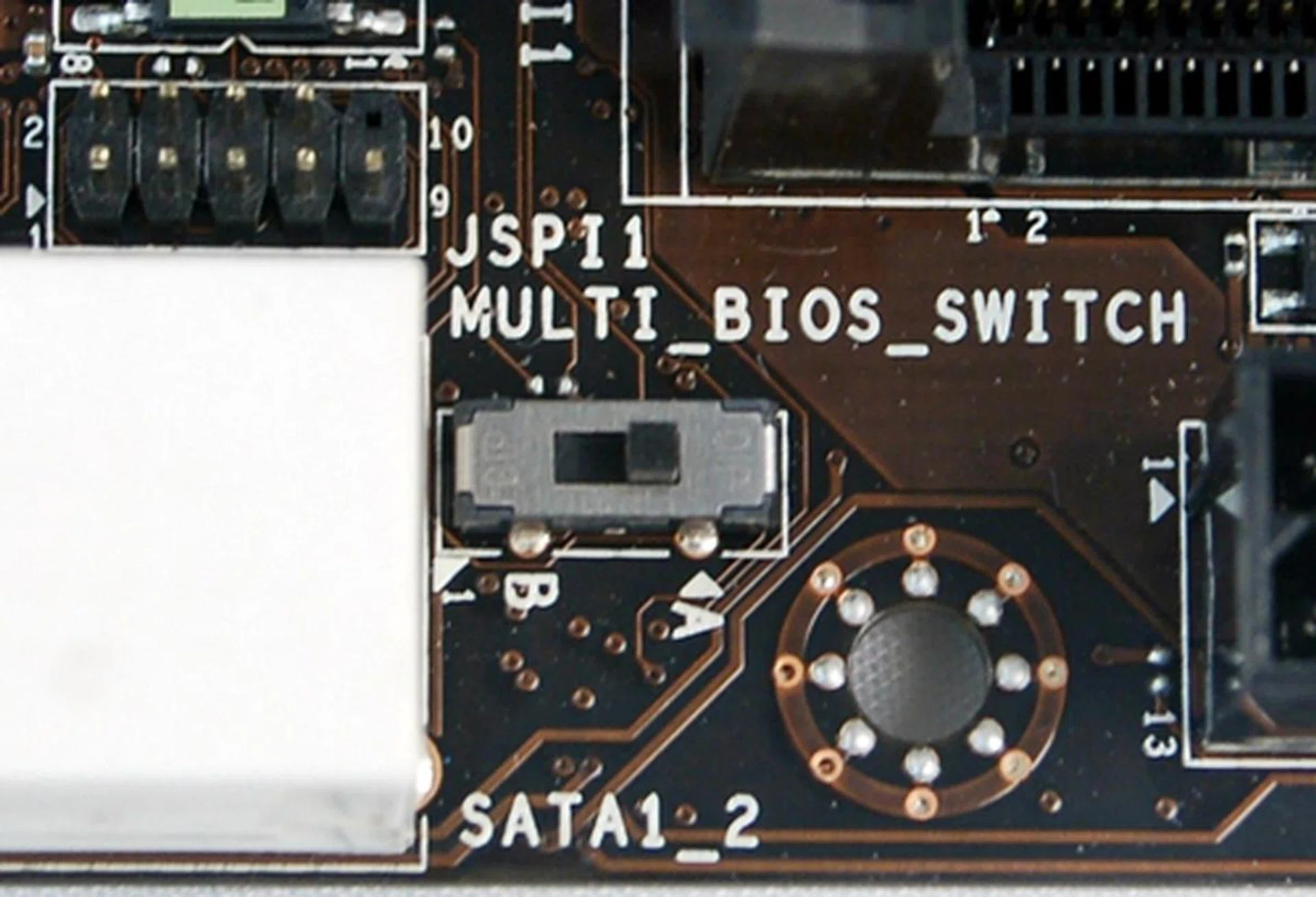 The Multi BIOS switch is located between the white SATA 6Gbps connector and the 24-pin ATX power connector. With the board in vertical orientation, flicking the switch upwards will toggle BIOS ROM A while BIOS ROM B is toggled when the switch is shifted down,