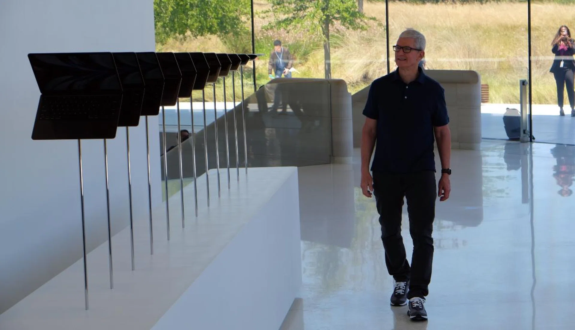Apple CEO Tim Cook walking past a display of new MacBook Airs.