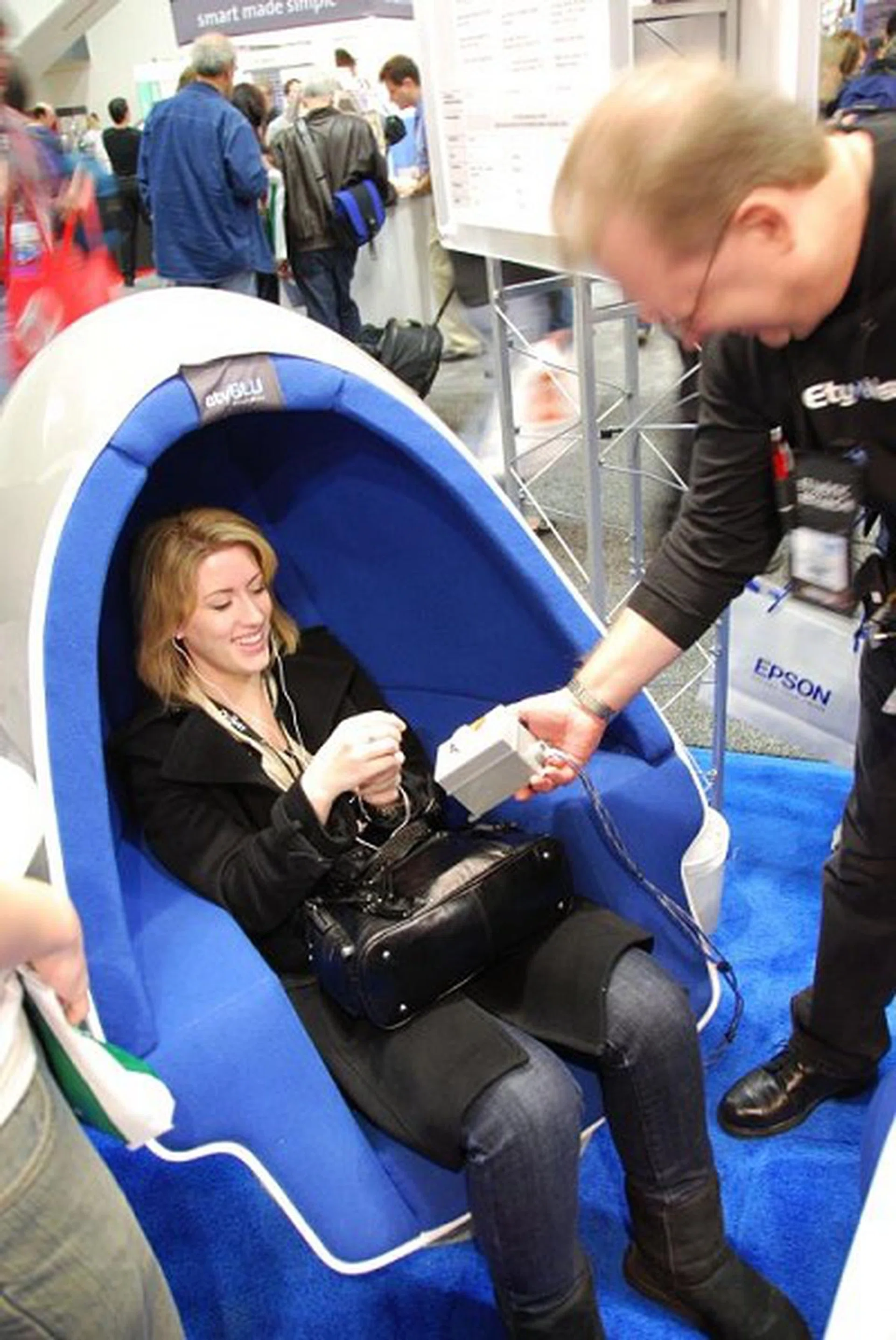 Etymotic Research had visitors listen to their latest in-ear headphones in an egg-chair where ambient sound can be tweaked by decibels. This lady is surprised by how good the in-ear headphones even when the ambient noise is tweaked to the loudest.