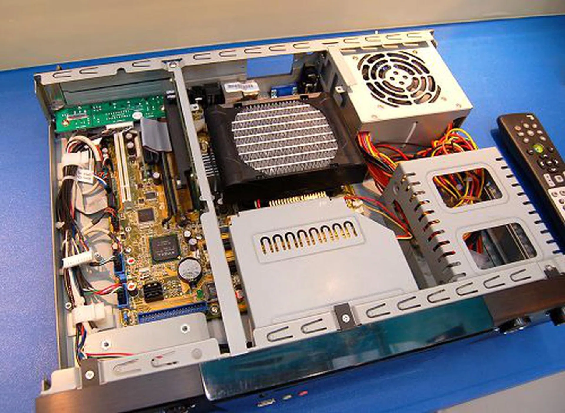  Here's the inside of the media center chassis. It contains a normal micro-ATX board and uses a riser card for PCI and PCIe expansion cards. The chassis integrates all necessary connectivity options like audio/video outputs up-front, and a wider array of A/V ports at the rear. It also integrates a card reader. The low profile but high performance CPU cooler is from Noise Limit.  