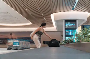 Pretty zehzeh collecting her check-in luggage from the luggage belt. Image credit: Changi Airport Group.