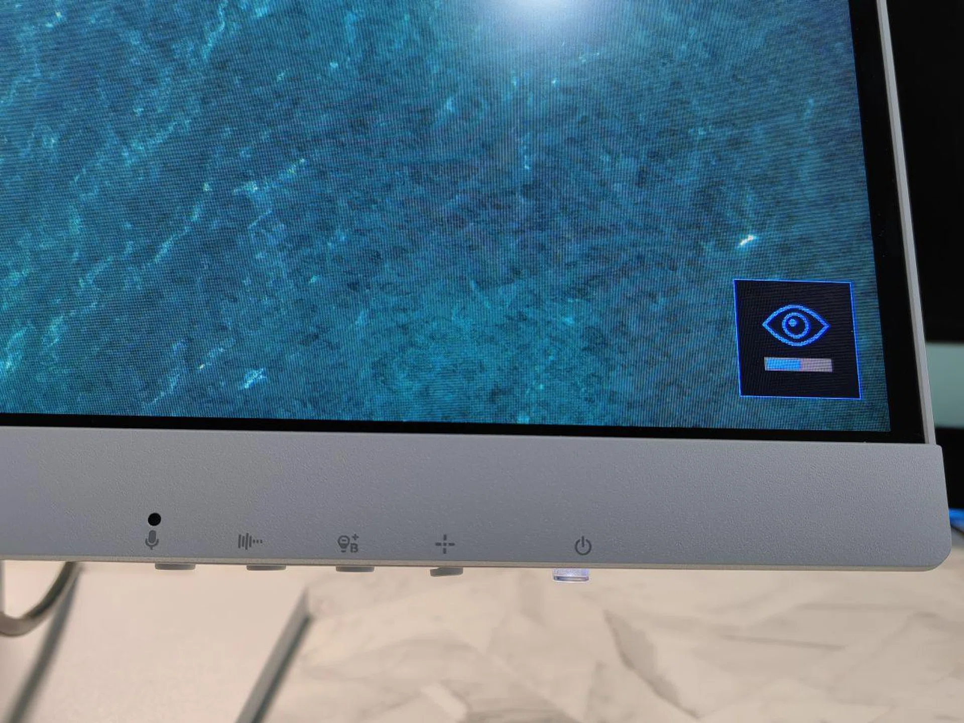 The buttons on the front right side of the monitor, including the lighted power button. Also shown is the on-screen prompt indicating that the monitor is currently adjusting the brightness.