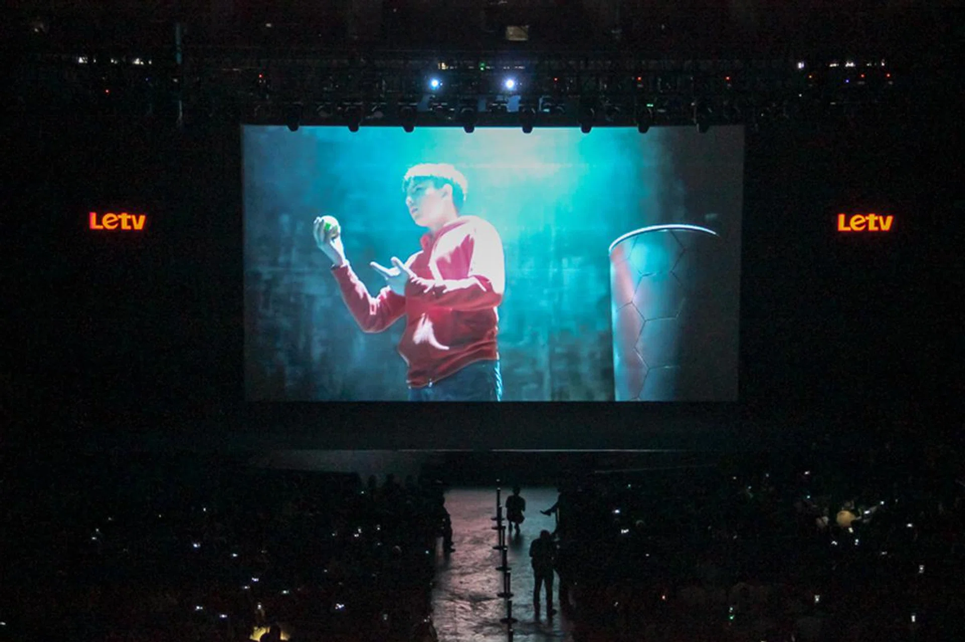 A young boy in red runs through the crowd, grabs the apple and takes a bite out of it.
