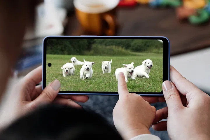 Close up of little Asian daughter sitting on mother's lap, using smartphone together at home. They are playing educational games on smartphone for e-learning. Family lifestyle and technology