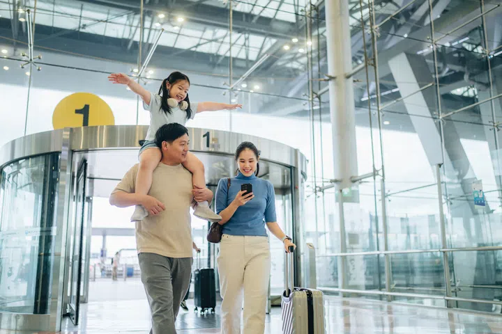 Family with luggage walking down the airport terminal,