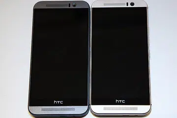 The new HTC One M9 comes in three different colors. Shown here is the gunmetal grey version (on the left) and the two-tone gold on silver design (on the right).
