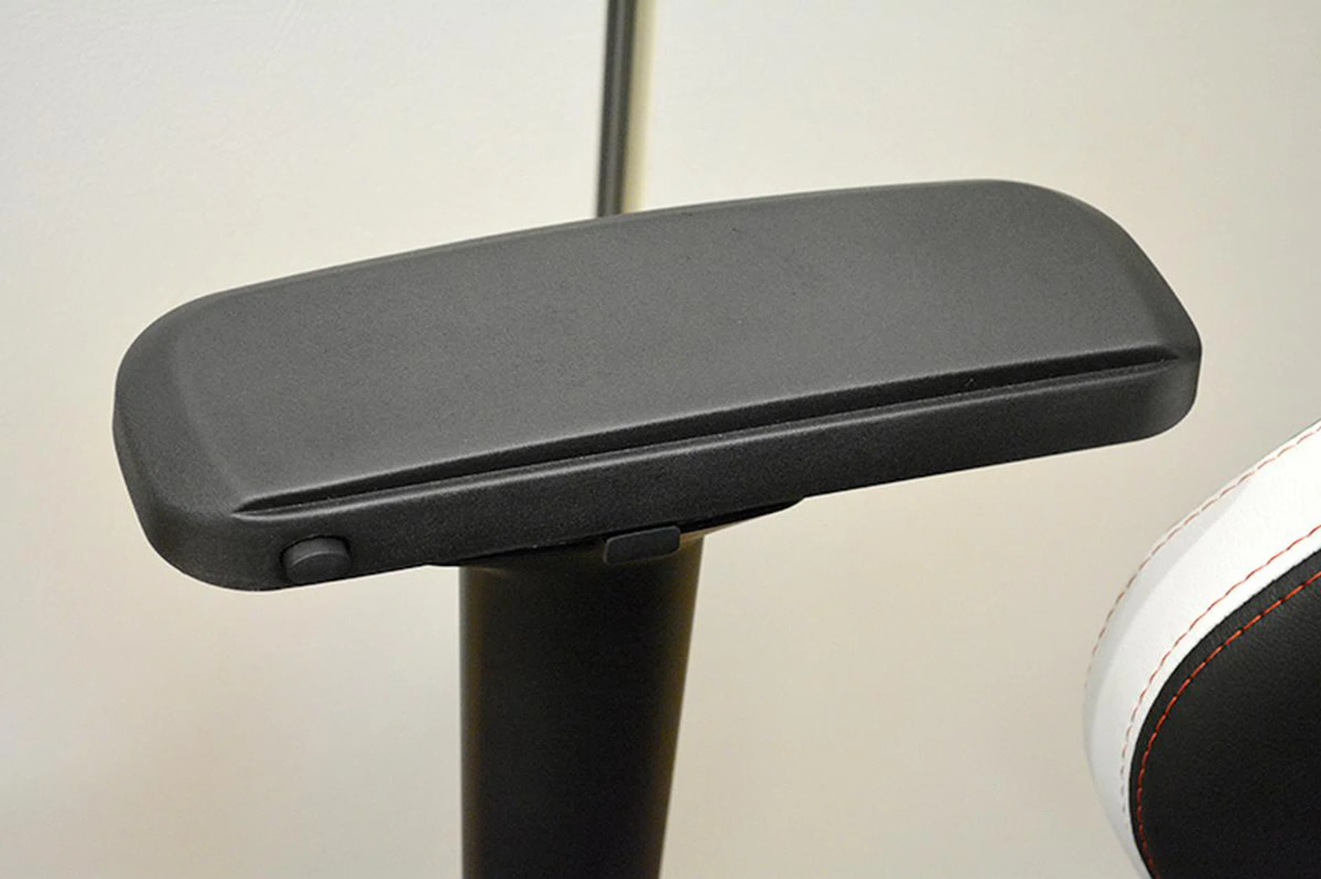 Pushing the button toward the front allows the armrest to move either forward or backward. The middle button activates the side adjustment mechanism.