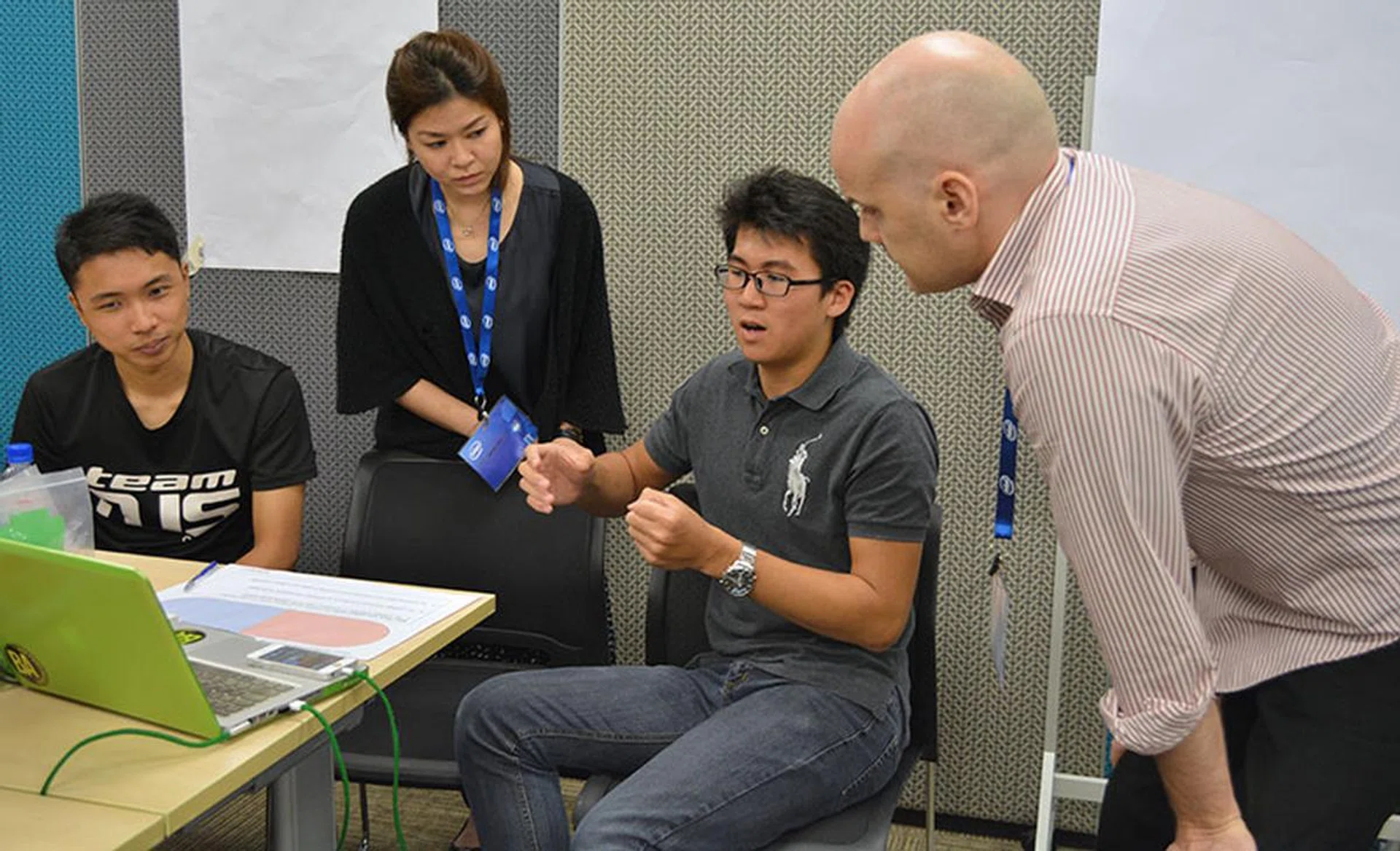 Team Stitches consulting with organizers. Their project involves devising a system to help elderly and disabled passengers board buses more easily.