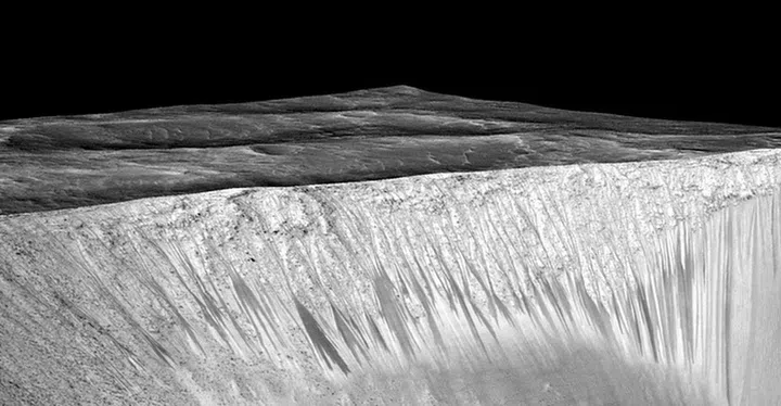 Dark narrow streaks called thought to be caused by water emanating out of the walls of Garni crater on Mars.<br>
Source: Mars Reconnaissance Orbiter/University of Arizona/JPL/NASA