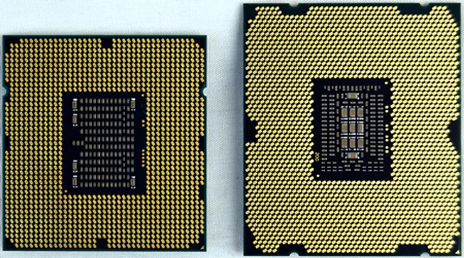 Shown here on their backs is their contact pads interfacing with the motherboard socket. On the left, the LGA1366 faces off with the LGA2011 on the right.