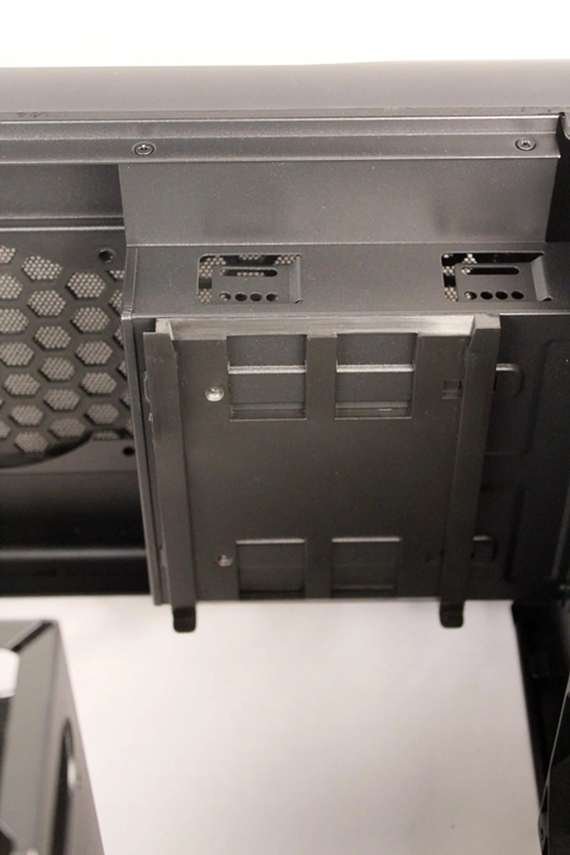 The plastic retaining component (which is on the flimsy side) attaches to the top of the 3.5-inch drive cage with the quick release clips. After its removal, it has to be re-aligned before the facing of both 3.5-inch cages can be changed.