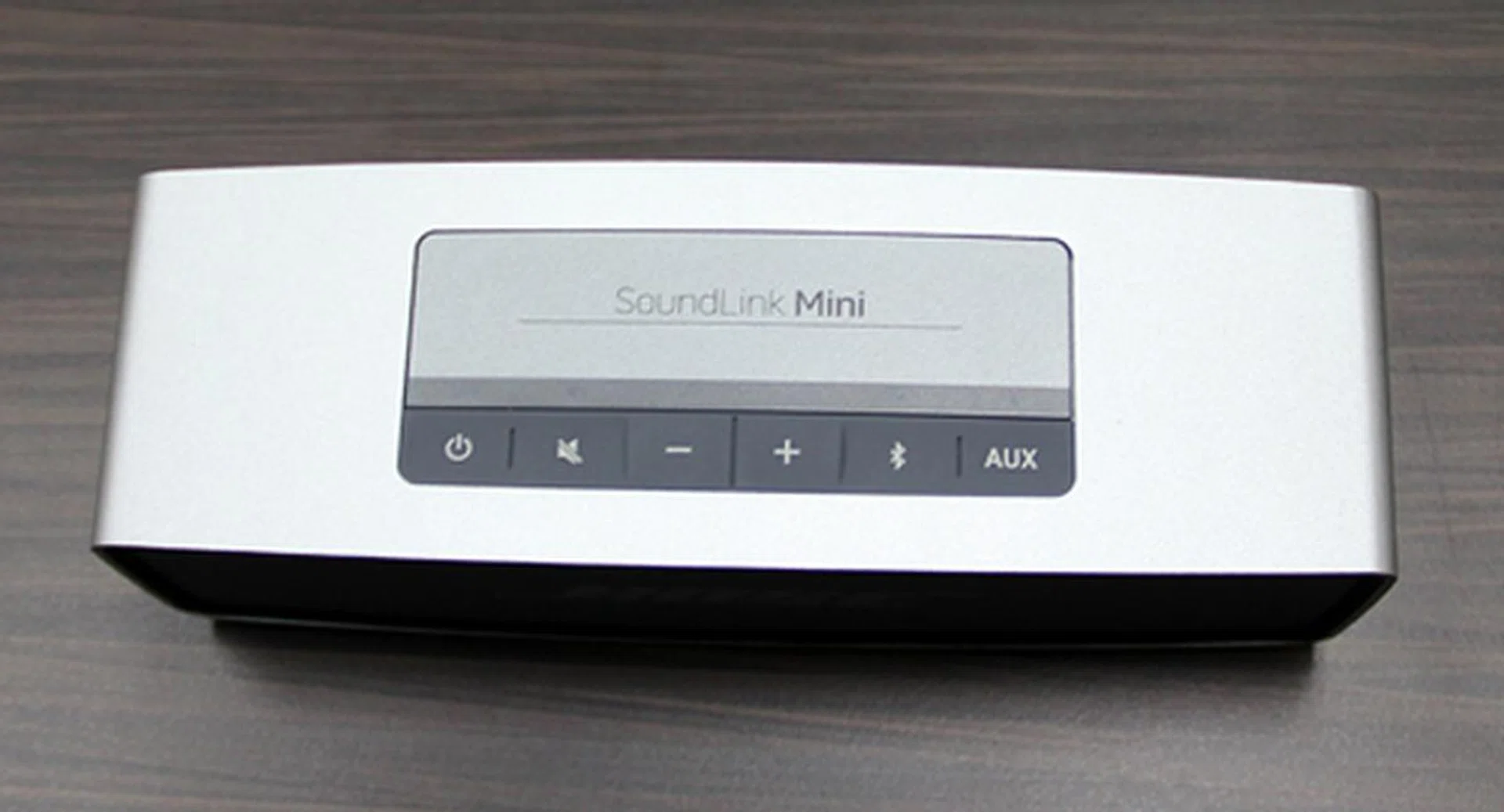 Controls for volume, power and source selection between AUX and Bluetooth are located on the top face.