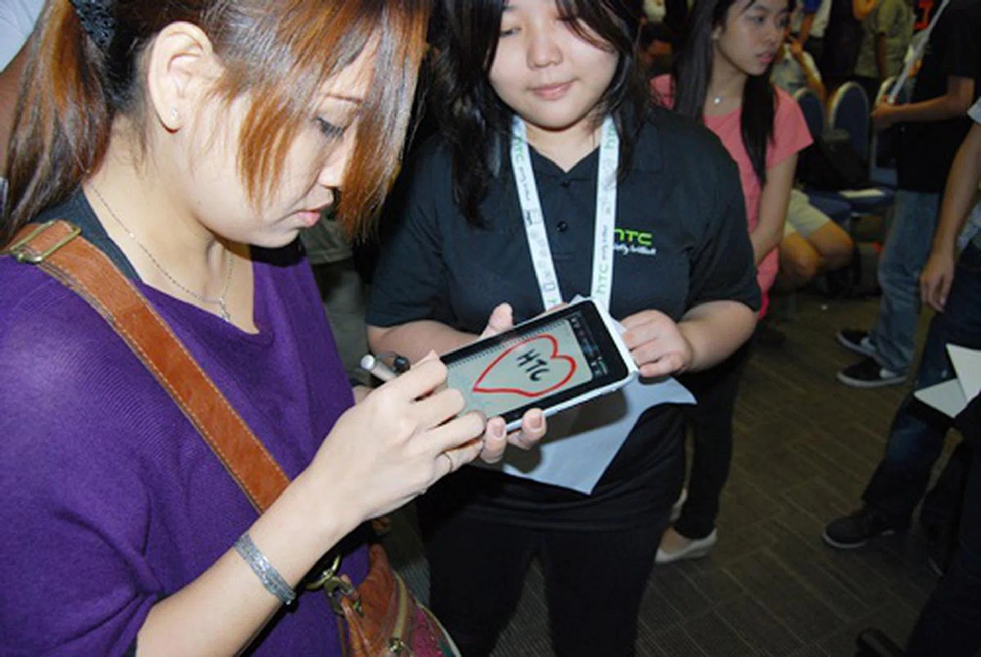 A HTC promoter showing an eager participant how to use the HTC Flyer's Scribe functions.
