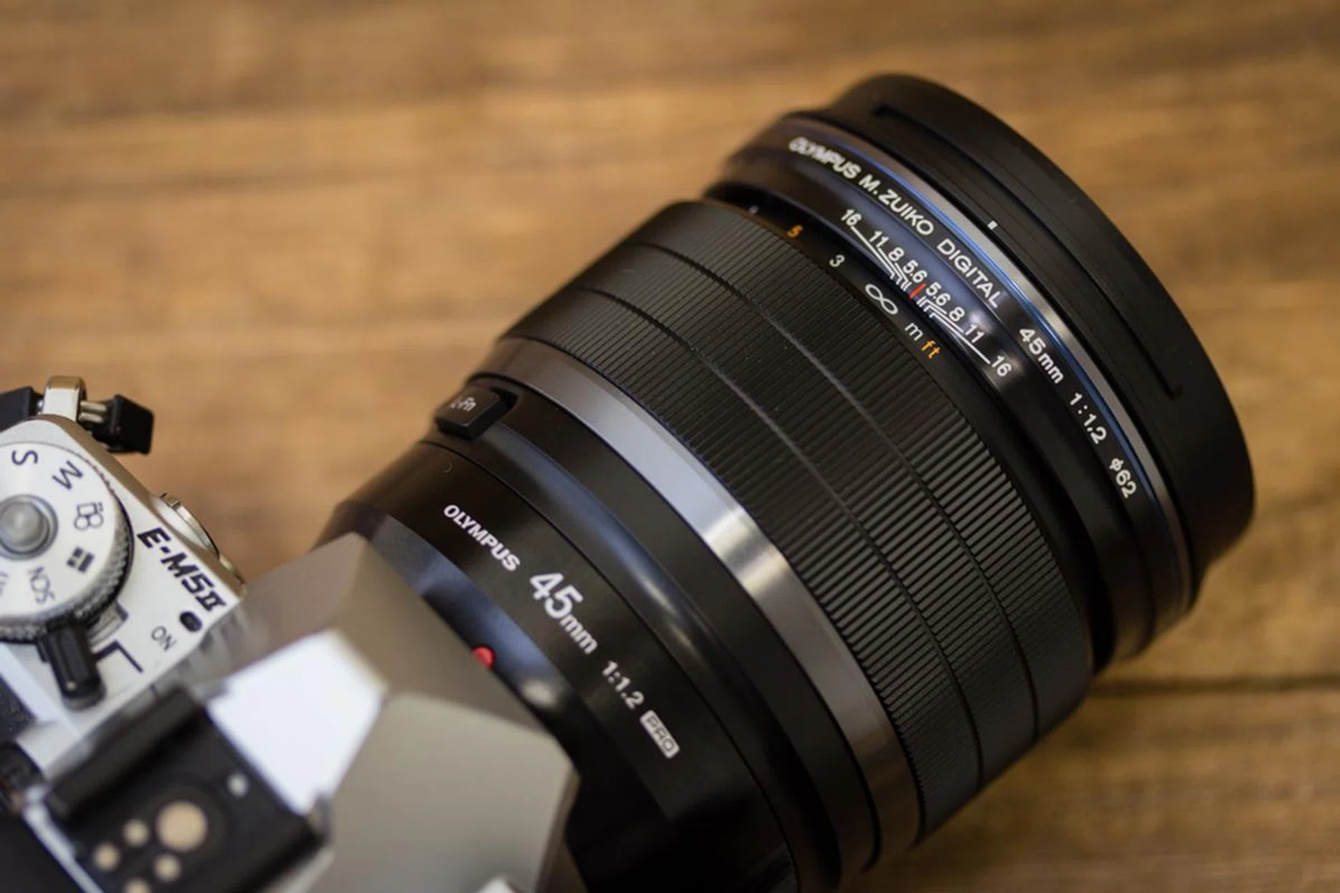 The Olympus lens has a manual focus clutch, which you can pull down to immediately engage manual focus.