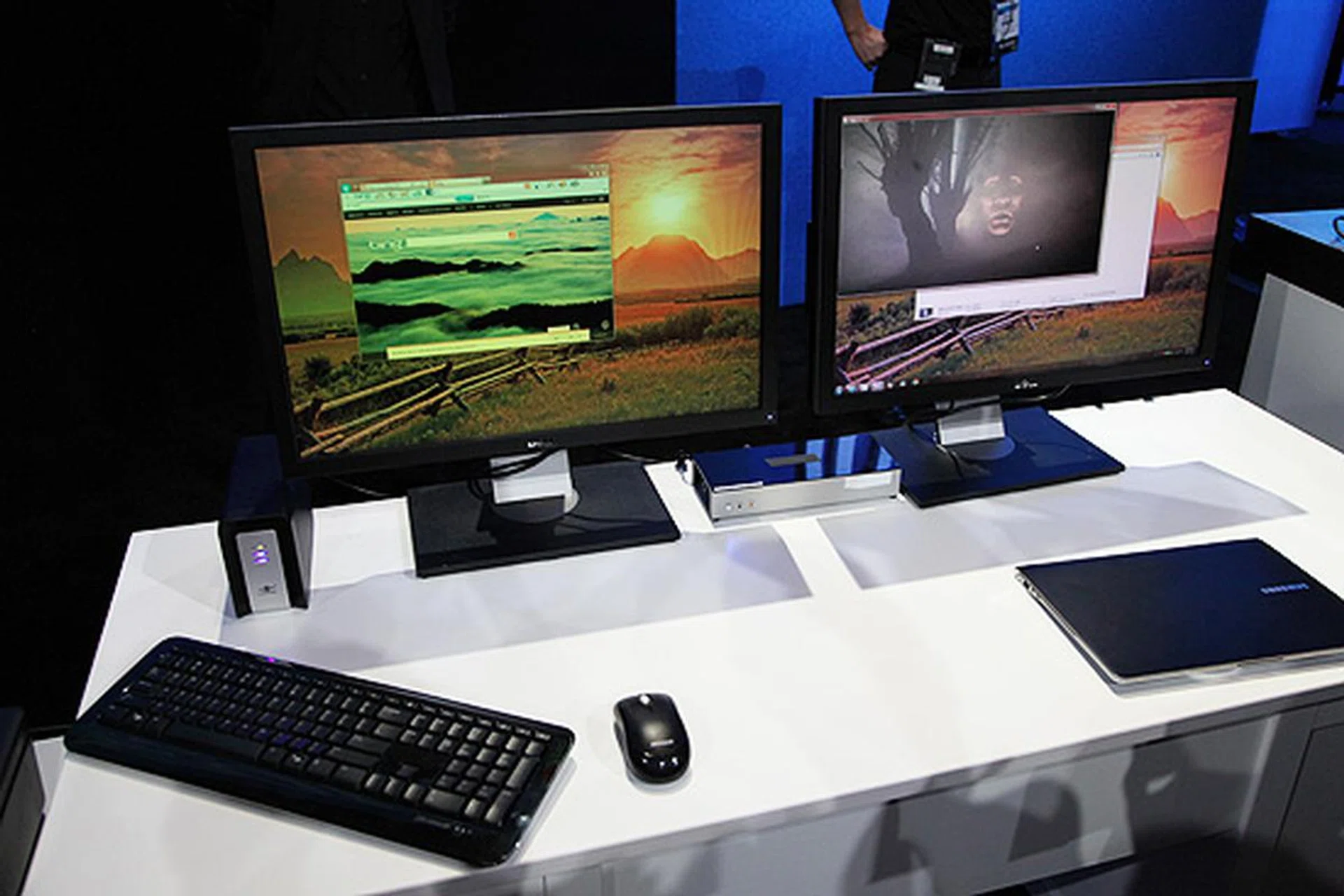 The WiGig demo with two wireless displays and a wireless storage drive (to the left) connected to the Ultrabook (to the lower right) without any cables. The WiGig prototype router is the black box with the white front panel located in between the two monitors.
