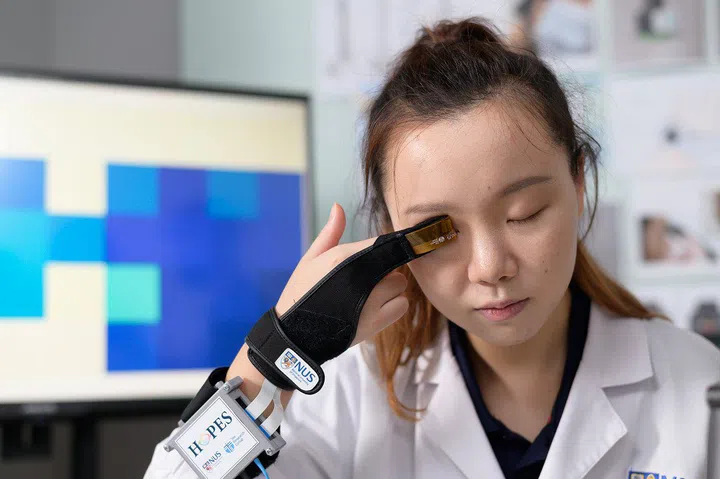 Ms Yu Kelu, demonstrating the use of HOPES, a pressure-sensitive fingertip on the glove that captures pressure information on the eye accurately in a non-invasive manner.