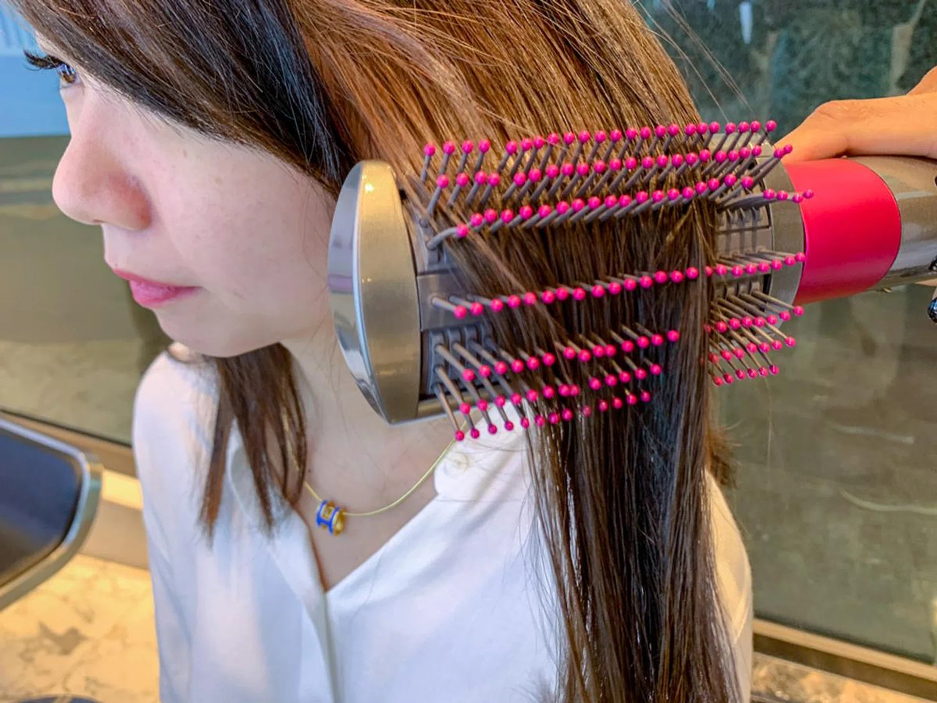 The soft smoothing brush’s air slots are pushing high-velocity air out, but thanks to the switching mechanism and the Coander effect, hair stays on the brush instead of flying away from it.