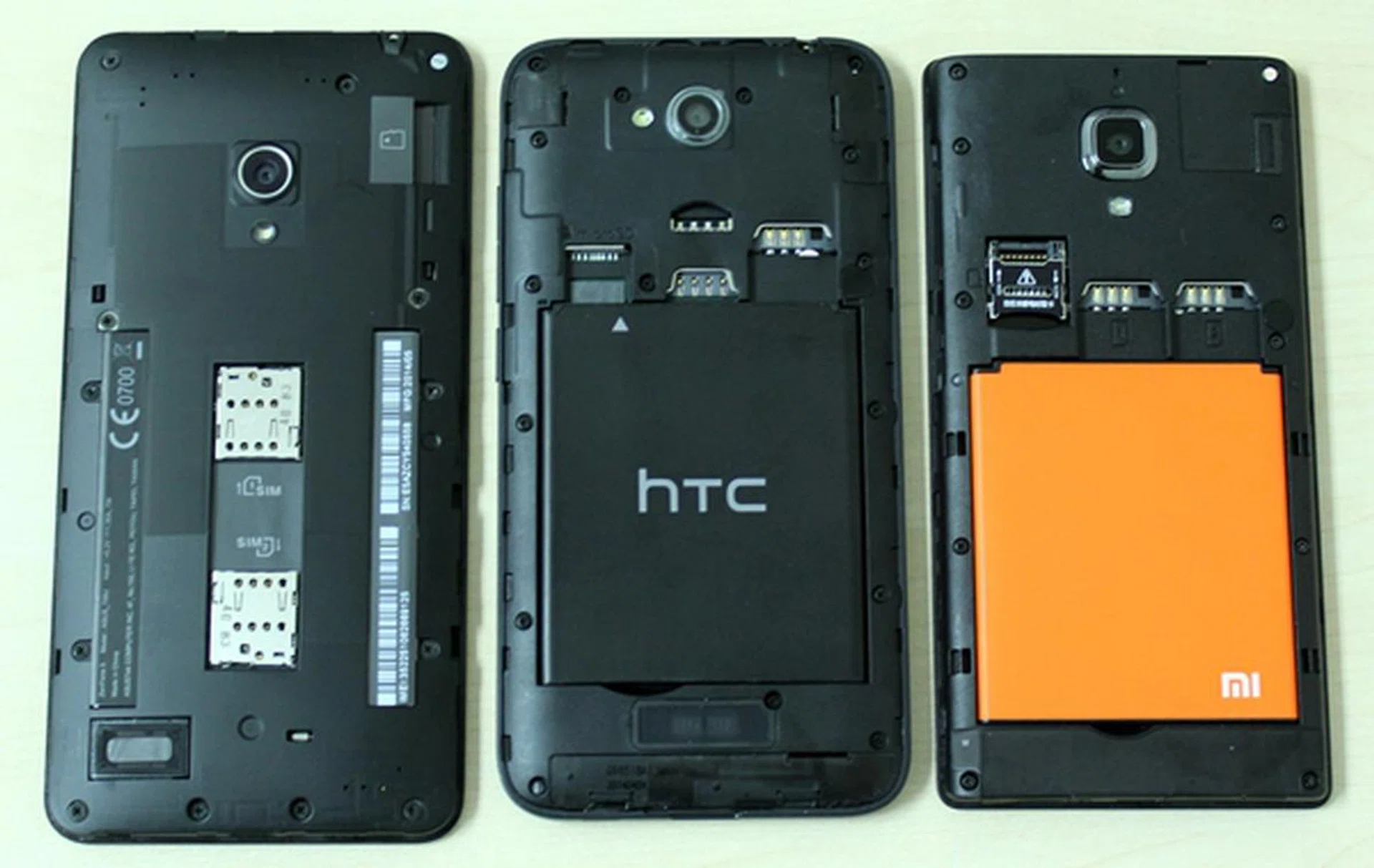 A look at the microSD and dual-SIM card slots on the three phones. <br> Left to right: ASUS ZenFone 5, HTC Desire 616 and Xiaomi Redmi 1S.