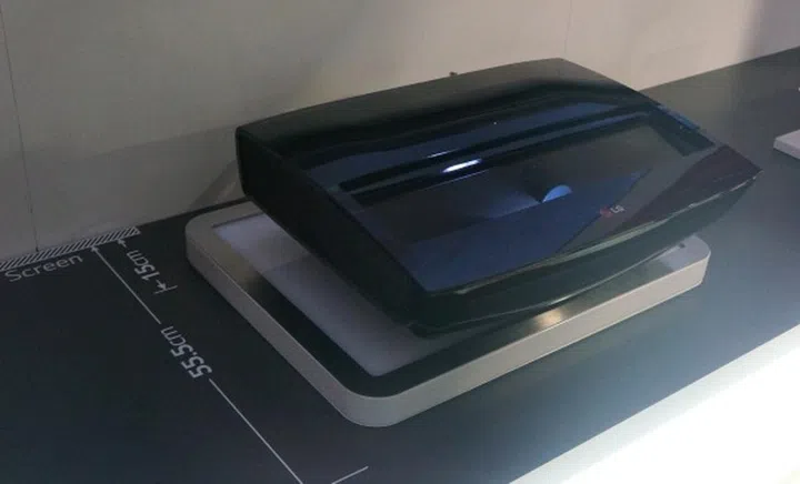 As seen in this photo, the unit can be placed as close to 15cm from the screen and  at that placement, the laser lens projection would be about 56cm from the screen.