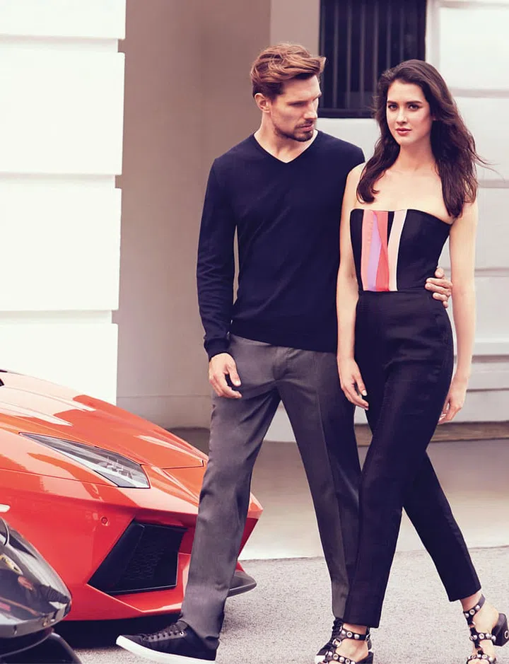 (On her) Jumpsuit, Roksanda at The Outnet. Heels, Michael Kors Collection. (On him) Sweater; sneakers, BOSS. Pants, CH Carolina Herrera 