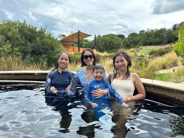 Asian mum with three kids in open-air, mineral-rich pools of the Peninsula Hot Springs in Victoria’s Mornington Peninsula.