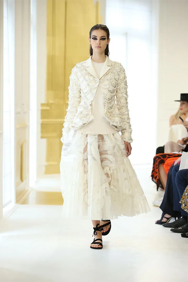 Ecru wool crêpe Bar jacket with sequin and silver thread “Junon” embroidery, ecru knit top and ecru silk tulle and lace pleated and embroidered skirt. Photo: Dior