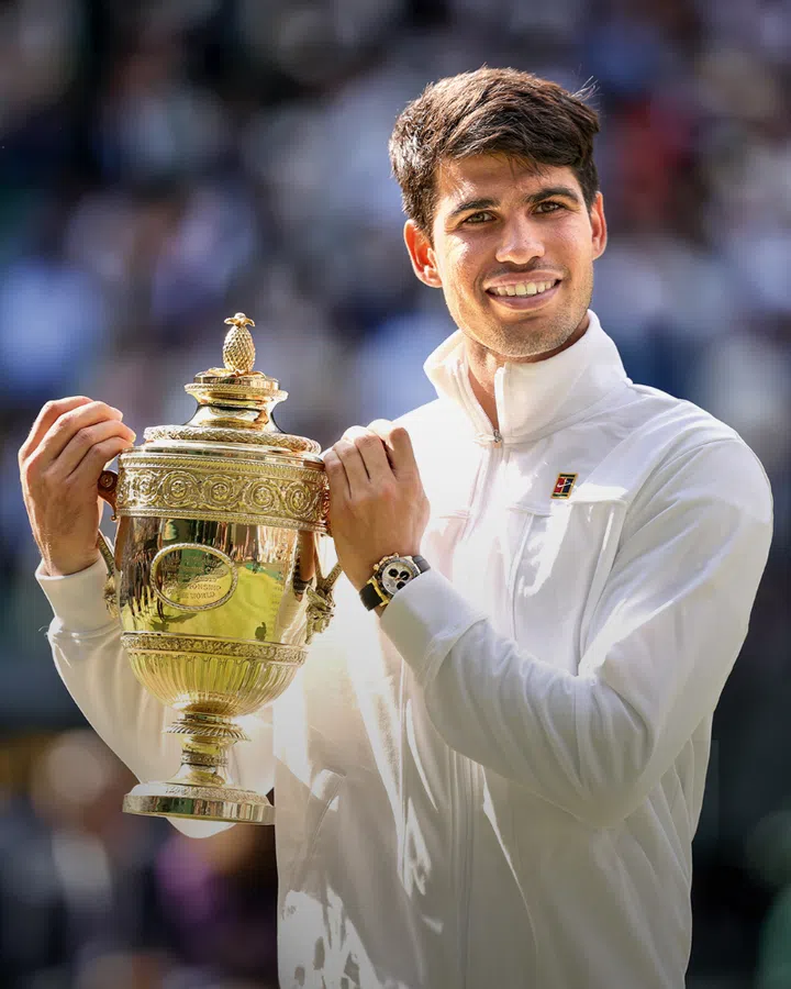 Carlos Alcaraz holding up his trophy at The Championships, Wimbledon 2024. 
