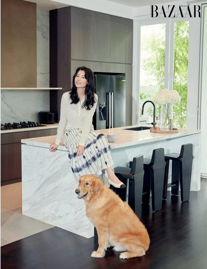 Relaxing with her dog Mao Mao on her kitchen counter in a top by Loro Piana, and her own skirt and Chanel pumps. Photo: Gan