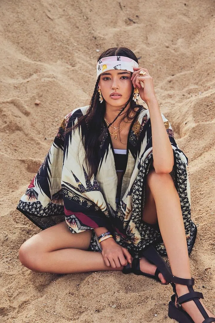 Poncho, Etro. Bikini set, Chanel. Scarf (around head); bangles; sandals, Hermès. Ring; earrings, Kate Spade New York. Necklaces, Louis Vuitton. Charm necklace, Dior. Necklace, model’s own. (Photo:  Phyllicia Wang)