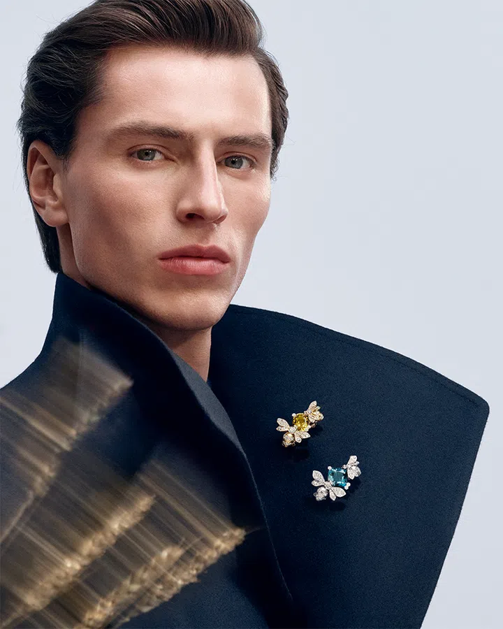 Model wears navy coat and Chaumet’s Jewels by Nature sapphire tourmaline bee brooches