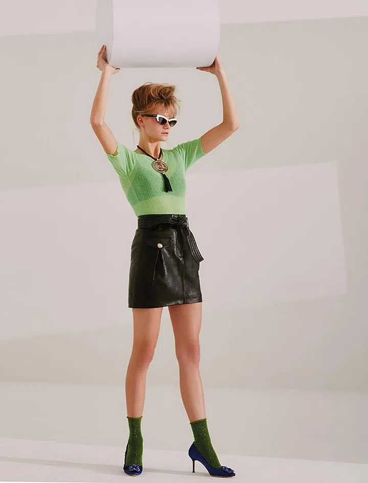 Leather skirt, Maje. Polyester-blend t-shirt, Sandro. Polyamideblend bra, Eres. Acetate sunglasses, Miu Miu. Leather and metal necklace, Longchamp. Satin pumps, Manolo Blahnik. Socks, stylist’s own.
