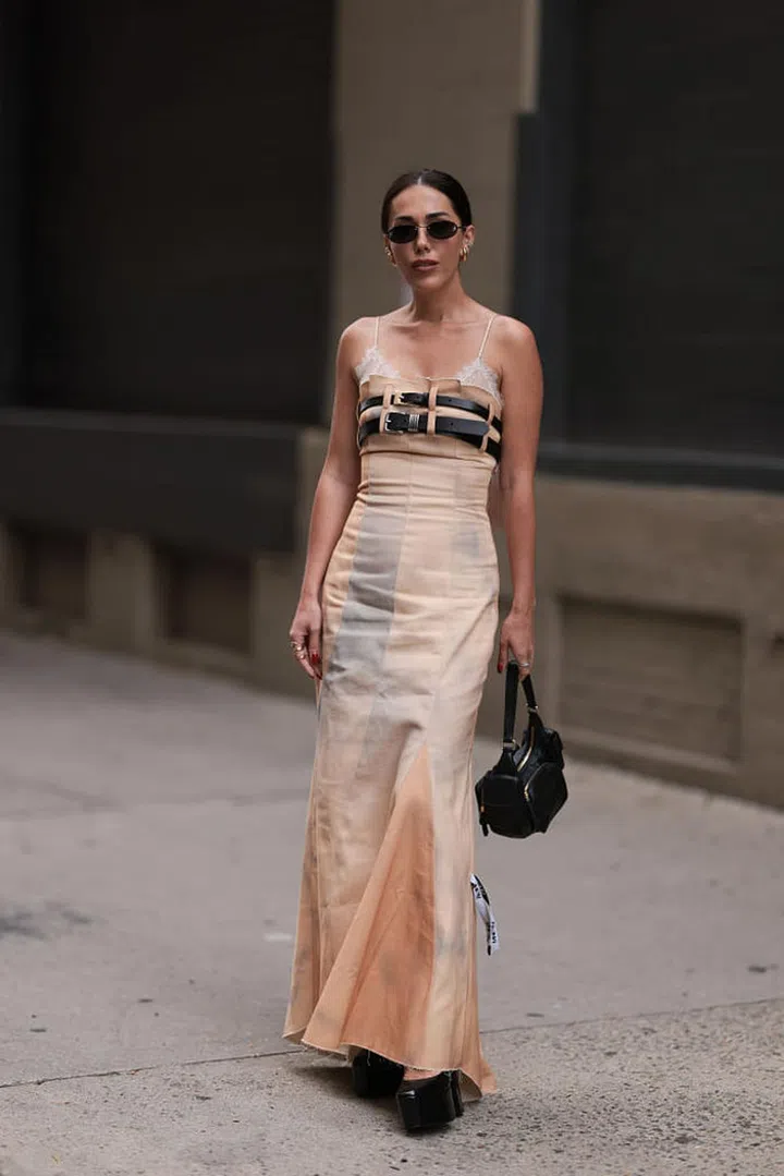 NEW YORK, NEW YORK - SEPTEMBER 09: Guest is seen outside Tibi show wearing black Fendi sunnies with crystal details, golden earrings, white lace bra, long orange and beige colored dress with belt details on breast, black MiuMiu handbag and black shiny plateau heels on September 09, 2023 in New York City. (Photo by Jeremy Moeller/Getty Images)
