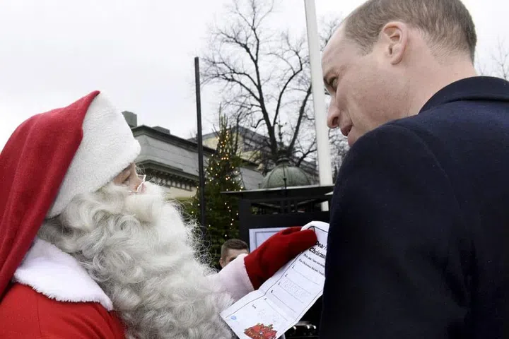 Prince William hands over a wish list from his son Prince George to Santa Claus as he visits the winter fair in Helsinki, Finland.