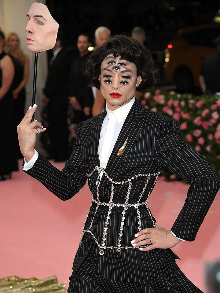 At the 2019 Met Gala in New York—with the theme being “Camp: Notes on Fashion”—all eyes were fixed on the men who were the most flamboyant. One star that stood out in particular was Ezra Miller. Wearing a Burberry by Riccardo Tisci pinstripe suit with a matching train under a sparkling corset and trompe l’oeil makeup, Miller echoes Hollywood’s new mood of acceptance, authenticity and the freedom of expression.