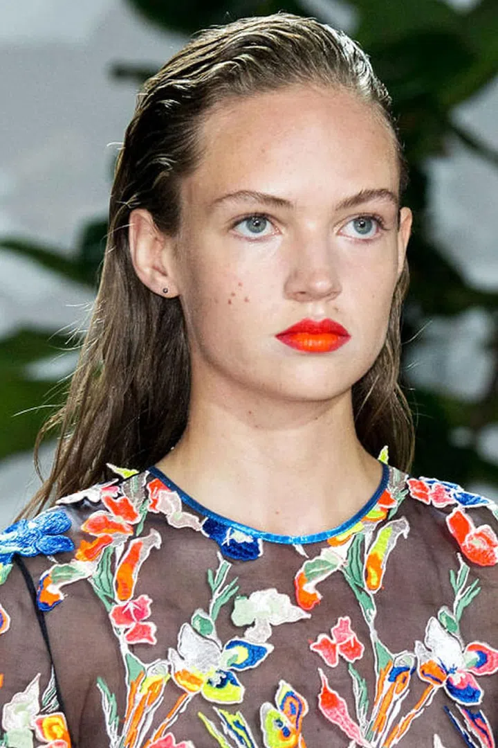 Jason Wu has always had a penchant for classic beauty. The man loves a red lip as much as the rest of us. This season, Wu served up exactly what you'd expect: a red lip. Kind of. Well, not really. "It's not your basic red, it's fluorescent red, if that exists," said makeup artist Yadim backstage. After applying a mix of two red lipsticks, he tapped some neon orange theater paint right in the center of the bottom lip. "It's a raver girl red," he says, imagining that girl thinking her basic red lipstick looks, well, basic. In his mind, she would smear on some neon paint before running out the door . The orange-red lips appeared on only a handful of models; the pop of color matched a similar shade on their gowns. All in all, it's the same Jason Wu girl we know and love, just cooler, sportier, and with a flair for neon.