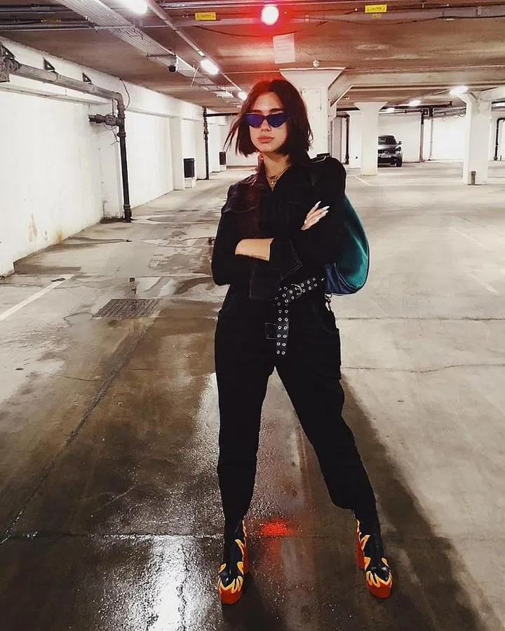 Dua is sporting an Orseund Iris workwear jumpsuit and leather belt with chain set on with a pair of Le Specs x Adam Selman sunglasses. The Vetements flame platform boots drive the look home with some sassy fiest. 
Photo: Instagram