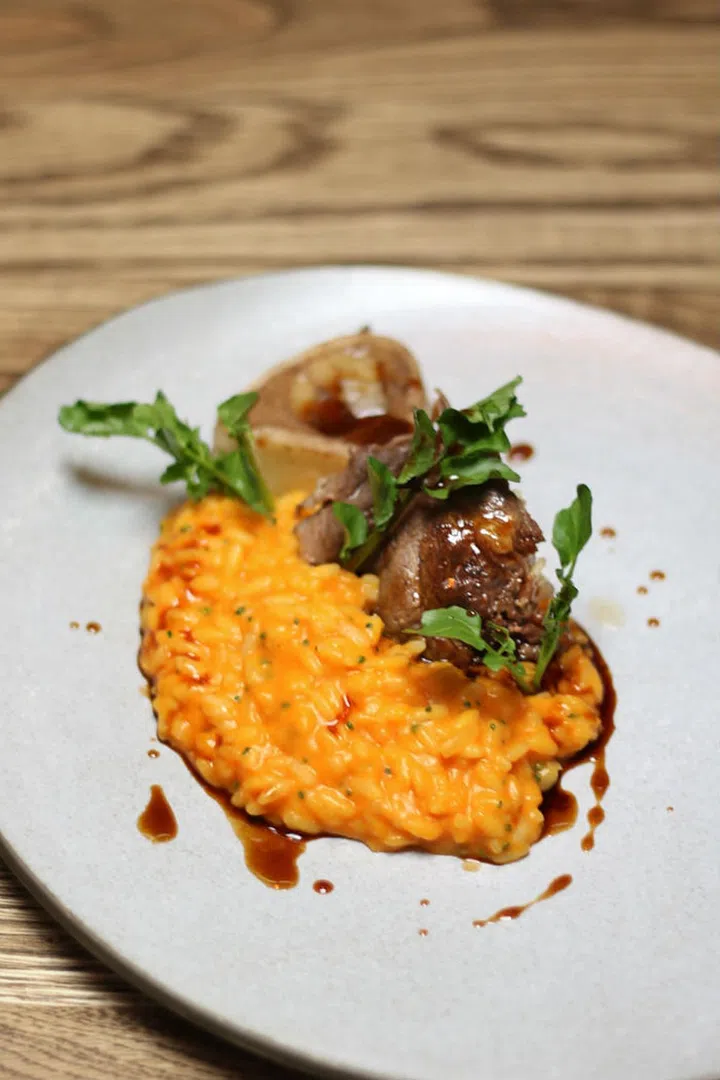 A fork-tender braised veal ossobuco with a full-bodied
carrot risotto and smoked paprika, and
watercress (harvested in-house).

Photo: Courtesy of Open Door Policy