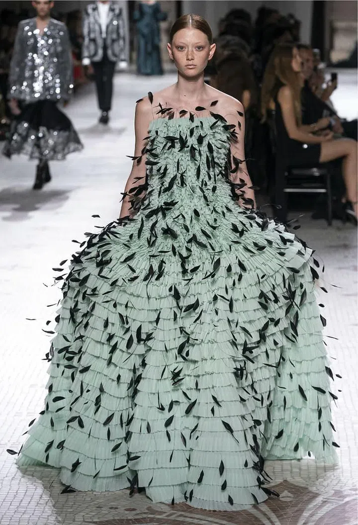 Clare Waight Keller has made refined elegance a cornerstone of her Givenchy haute couture, but this season, she also threw in a hint of rebellion to shake things up. Silhouettes that started rigorously tailored ended in raw-edged fringe or trailing ribbons on the floor. Despite the note of punk she inserted—most prominently in the form of sweeping, spiky updos on some of the models—her default mode was polish. The silhouettes were extravagant, but expertly sculpted; the bursts of feathers and taffeta were all carefully engineered. When she did use colour, it was in the form of opulent texture—silver embroideries, emerald brocade, plumage in coral and mint. It was a masterful balancing act between razzle-dazzle and restraint. 

Photo: Courtesy