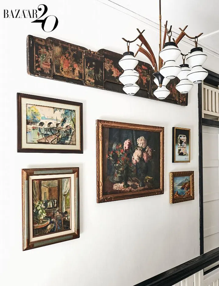 A mid‐century Italian chandelier hangs in front
of vintage paintings in the upstairs corridor, most of which were procured at flea markets in France.

(Photo: Phyllicia Wang)