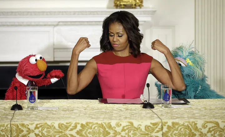 First lady Michelle Obama, center, flexes her arms for PBS Sesame Street's characters Elmo, left, and Rosita, right, during an event to help promote fresh fruit and vegetable consumption in the State Dining Room of the White House in Washington, Wednesday, Oct. 30, 2013. Sesame Workshop and the Produce Marketing Association (PMA) joined in Partnership for a Healthier America (PHA) in announcing a 2-year agreement to making healthy choices by using the Sesame Street characters to help deliver the messages about fresh fruits and vegetables. (AP Photo/Pablo Martinez Monsivais) ** Usable by LA and DC Only **