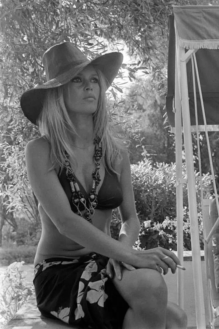 Channel your inner Brigitte Bardot by the beach or the pool in a wide-brimmed hat, an oversized beaded necklace, triangle bikini and floral sarong.