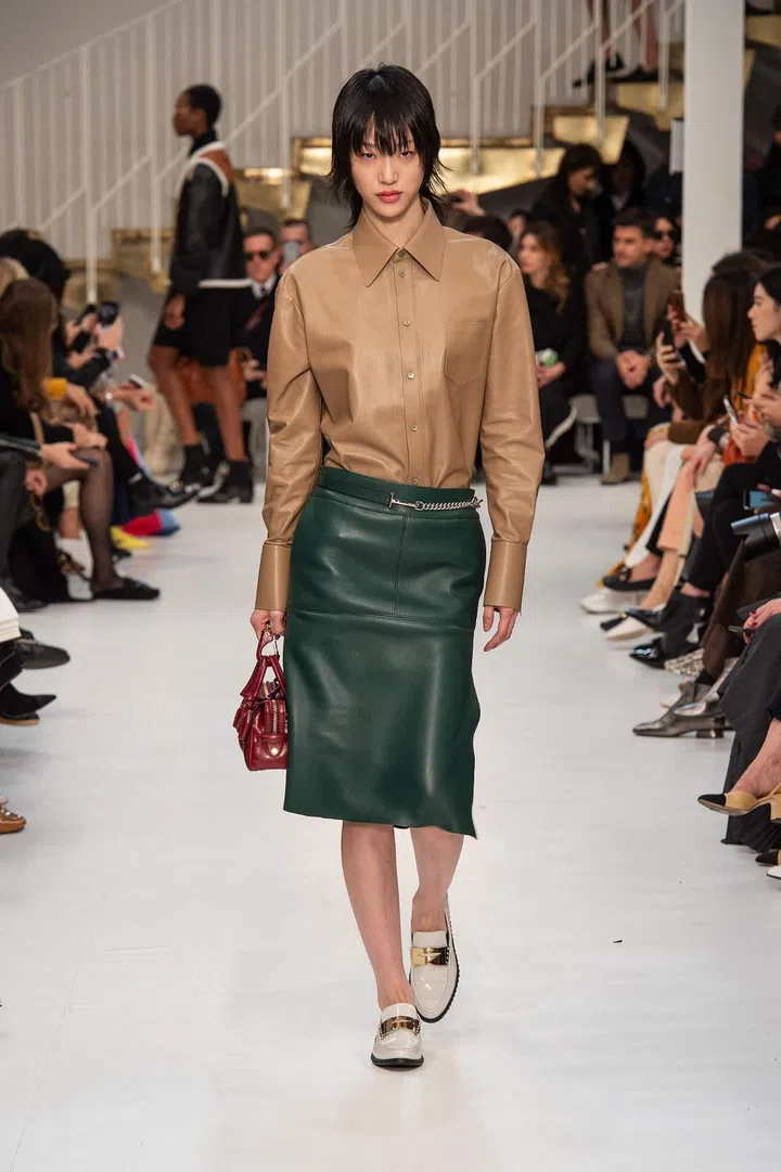 Staying true to House codes, leather
reigned supreme, emerging in a variety of
silhouettes, finishes and dyes. From
structured but supple Napa trenches to
feather-light dresses, the artisans gave the clothing a luminosity usually only seen in high shine patent leather pieces. Of course, one would expect nothing less from an Italian brand steeped in modern
sophistication. The colour palette was
warm and refined: Shades of black,
caramel and ivory intermingled with
brushes of powder pink, bottle green, and
burgundy, all executed in leather with
finesse. Where there wasn’t leather, there
were fuzzy wool coats, Mediterranean inspired jacquard knits and checked trenches belted with Tod’s identifiable double-T clasp, tied together with
multiple versions of the D-styling bag, an ode to the late Princess Diana’s legendary chic.